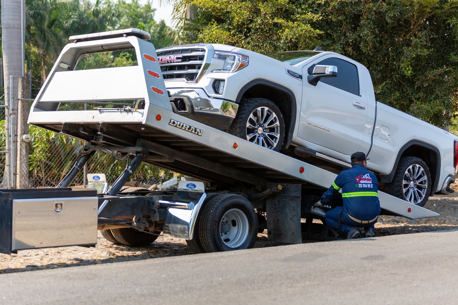 A Snappy Towing technician safely securing a vehicle onto a flatbed tow truck on a clear day in Indianola, Iowa.